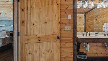 Una puerta de madera con manija, un baño con lavamanos y un espejo.