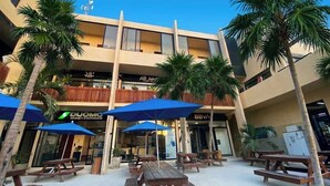 A hotel with outdoor seating, palm trees, and a money exchange. - Ananda Hotel Boutique (Isla Holbox)