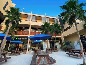 A hotel with outdoor seating, palm trees, and a money exchange. - Ananda Hotel Boutique (Isla Holbox)
