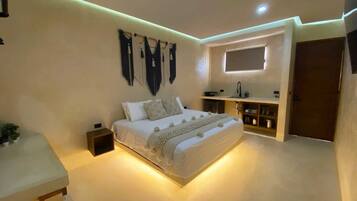 A modern bedroom with a bed, bedside table, wall-mounted artwork, and a built-in shelf with a mirror.