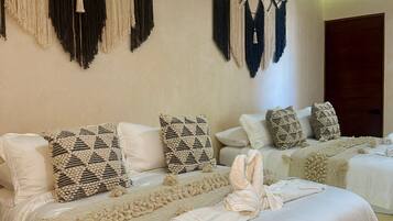 A hotel room with two beds, each with patterned pillows and a decorative macrame wall hanging.