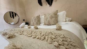 A bedroom with a large bed, a round mirror, and decorative pillows.
