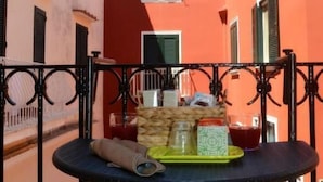 Μια αυλή με ένα τραπέζι στρωμένο για φαγητό στην ύπαιθρο, περιτριγυρισμένη από κτίρια με διακριτά αρχιτεκτονικά στυλ.
