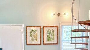 A kitchen with a dining table, chairs, a hanging light fixture, framed botanical prints, and a window with blinds. - Family Favorite Beach & Golf Condo with a View (Edisto Island)