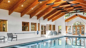 A spacious indoor pool area with wooden beams, large windows, and a view of the outdoors. - Luxury Mountain Estate w/ Indoor Pool, Gym & Hot Tub Near Keystone | Sleeps 19 (Keystone)