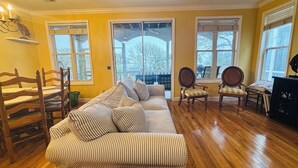 Un salon avec un canapé à rayures, des chaises en bois et un ventilateur de plafond.