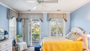 Une chambre à coucher avec un lit, une chaise, un bureau et un ventilateur de plafond.