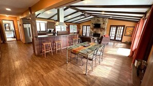 A spacious open-plan living area with a dining table, kitchen, and stone fireplace.