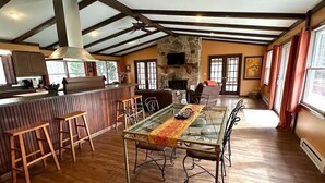 A spacious dining area with a long table, wooden stools, and a stone fireplace.