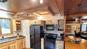 A modern kitchen with wooden cabinets, a black refrigerator, a stove, and a microwave.
