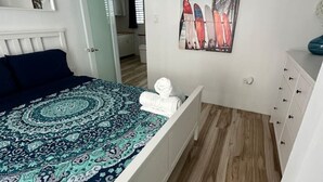 A bedroom with a bed, a dresser, a painting, and a hallway leading to another room. - Casa Rosado @ Rincon Rayo Suite Mountain View Pool (Cruces)