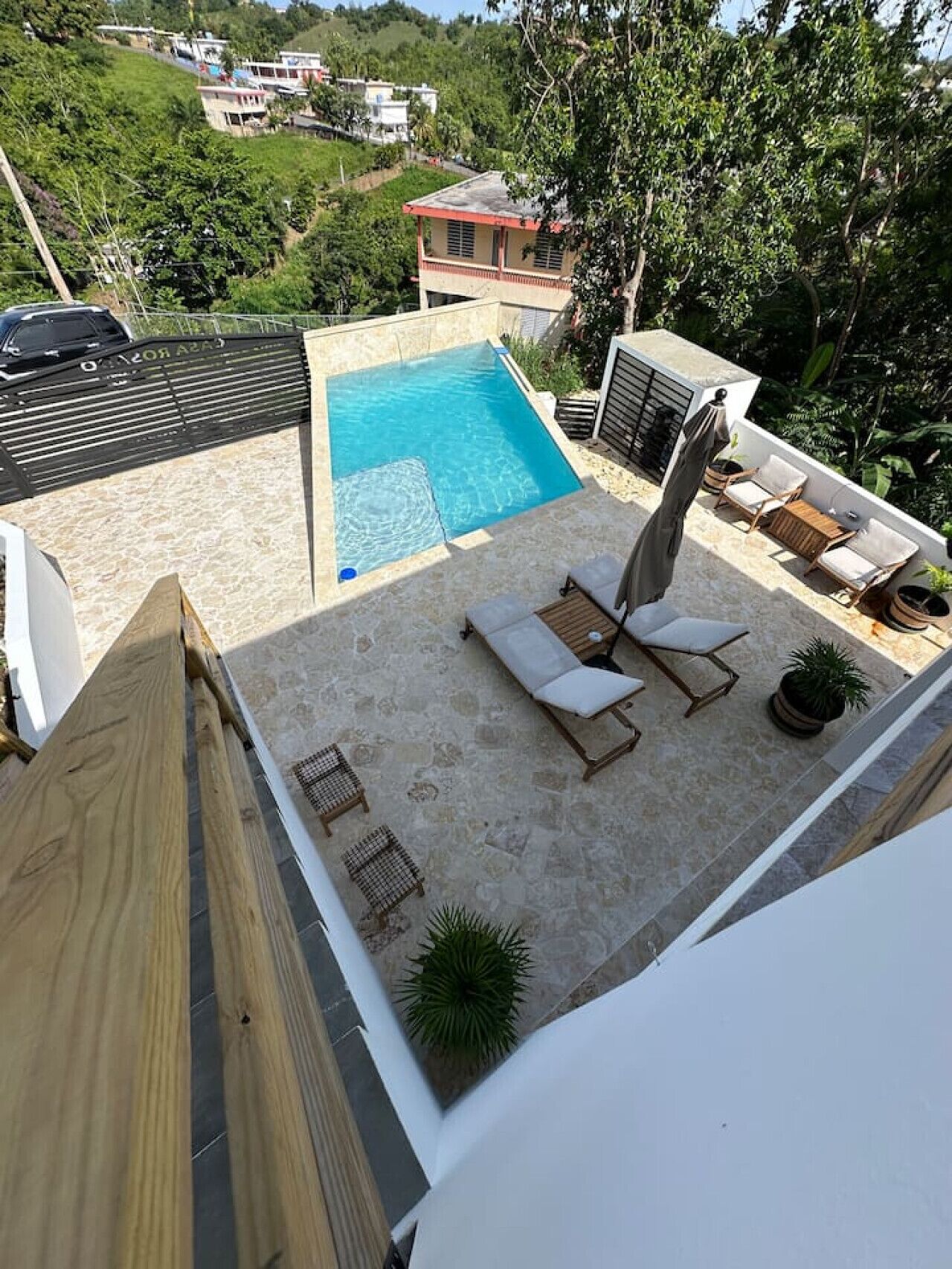 A rooftop pool area with lounge chairs and potted plants.