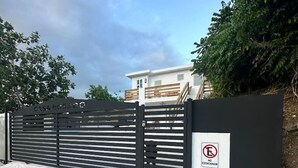 Una entrada cerrada con un letrero de no estacionamiento, un camino de piedra y un edificio moderno al fondo.