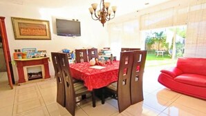 A dining area with a red tablecloth, wooden chairs, a chandelier, a television on the wall, and a red sofa in the living area. - Spacious 4 bedroom&Pool and 2 jacuzzis, WiFi, AC In Amazing area in San Salvador (San Salvador)