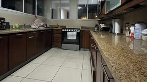 A kitchen with dark wooden cabinets, a granite countertop, and a tiled floor. - Spacious 4 bedroom&Pool and 2 jacuzzis, WiFi, AC In Amazing area in San Salvador (San Salvador)