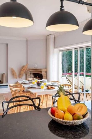 Un comedor con una mesa dispuesta para el desayuno, un frutero y una chimenea.