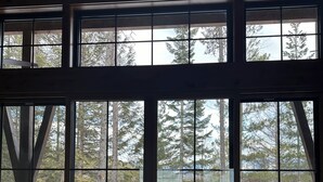 Ein Zimmer mit großen Fenstern und Blick auf eine verschneite Landschaft sowie hohe Bäume.