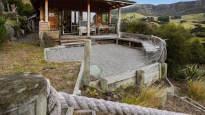 Une cabane en bois dotée d’un patio couvert, de meubles d’extérieur et offrant une vue panoramique sur une colline.