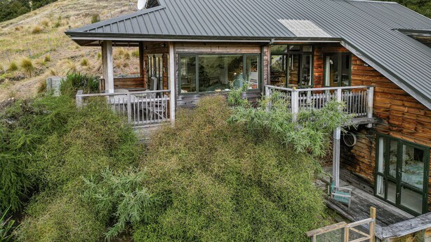 Une cabane en bois avec un toit en métal, de grandes fenêtres et une terrasse.