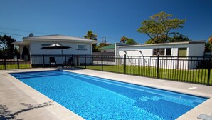 Ein rechteckiger Swimmingpool mit klarem, blauem Wasser, umgeben von einem schwarzen Metallzaun.