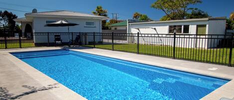 Una piscina rectangular con agua azul cristalina, rodeada por una valla de metal negro.
