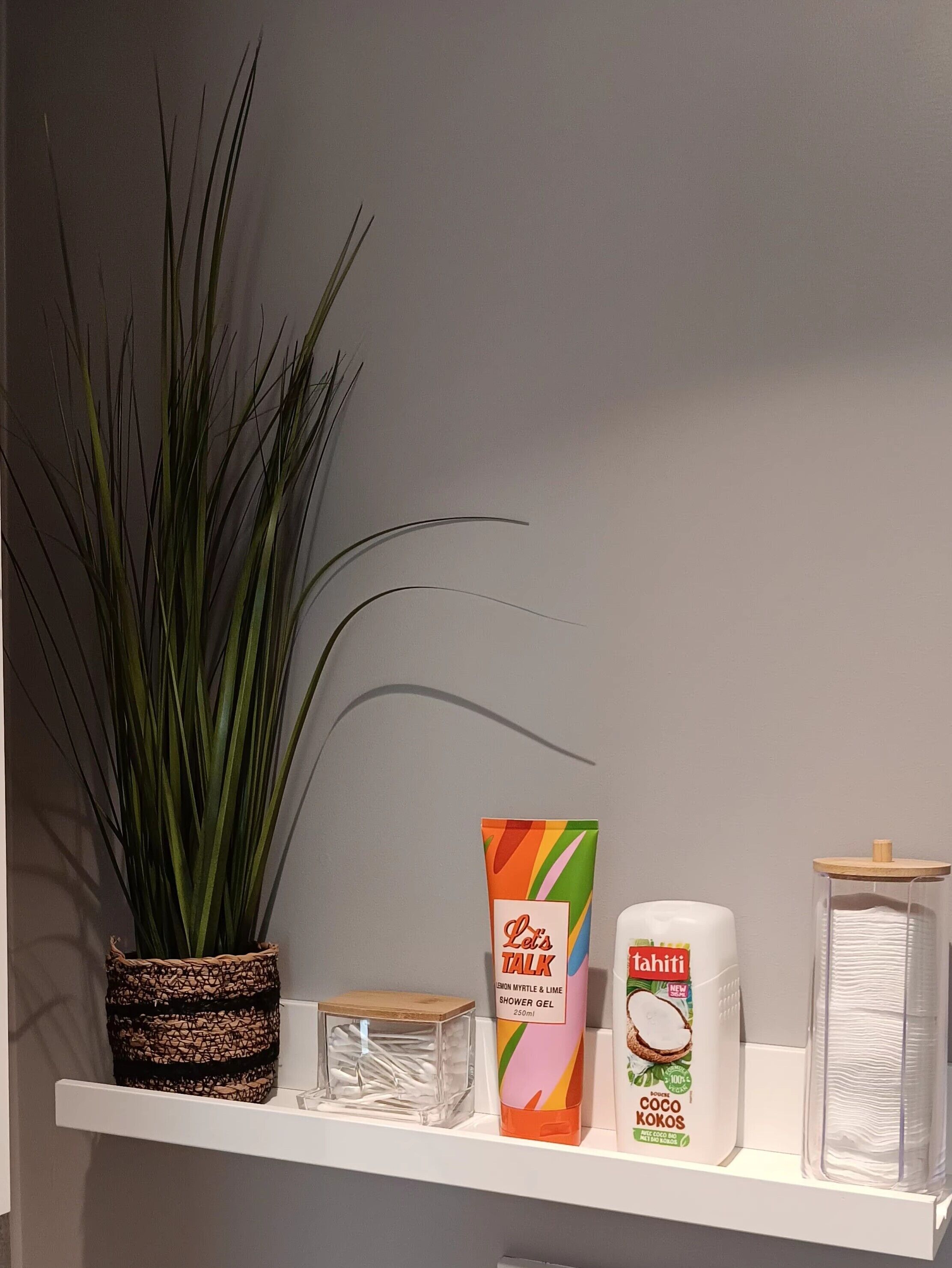 Een plank met een bloempot, een kleurrijke doos met de tekst 'Let's TALK' en twee toiletartikelen.