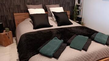 A neatly made bed with a black and white patterned bedspread, two black pillows, and a teal towel.
