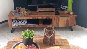 A modern living room with a wooden entertainment unit, a flat-screen TV, and a coffee table with decorative items.