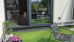 A modern home with a sliding glass door leading to a patio with a dining area and a small garden.