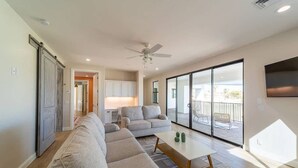 A modern living room with a sofa, a coffee table, and a view of a balcony.