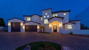 A modern two-story house with a driveway, garage, and landscaped front yard.