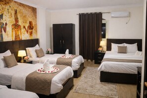 Une chambre d’hôtel avec deux lits, un grand tableau au mur, une armoire et un appareil de climatisation.
