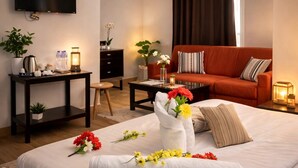 Ein Hotelzimmer mit Bett, Fernseher, Sofa, Couchtisch und Schreibtisch mit Lampe.