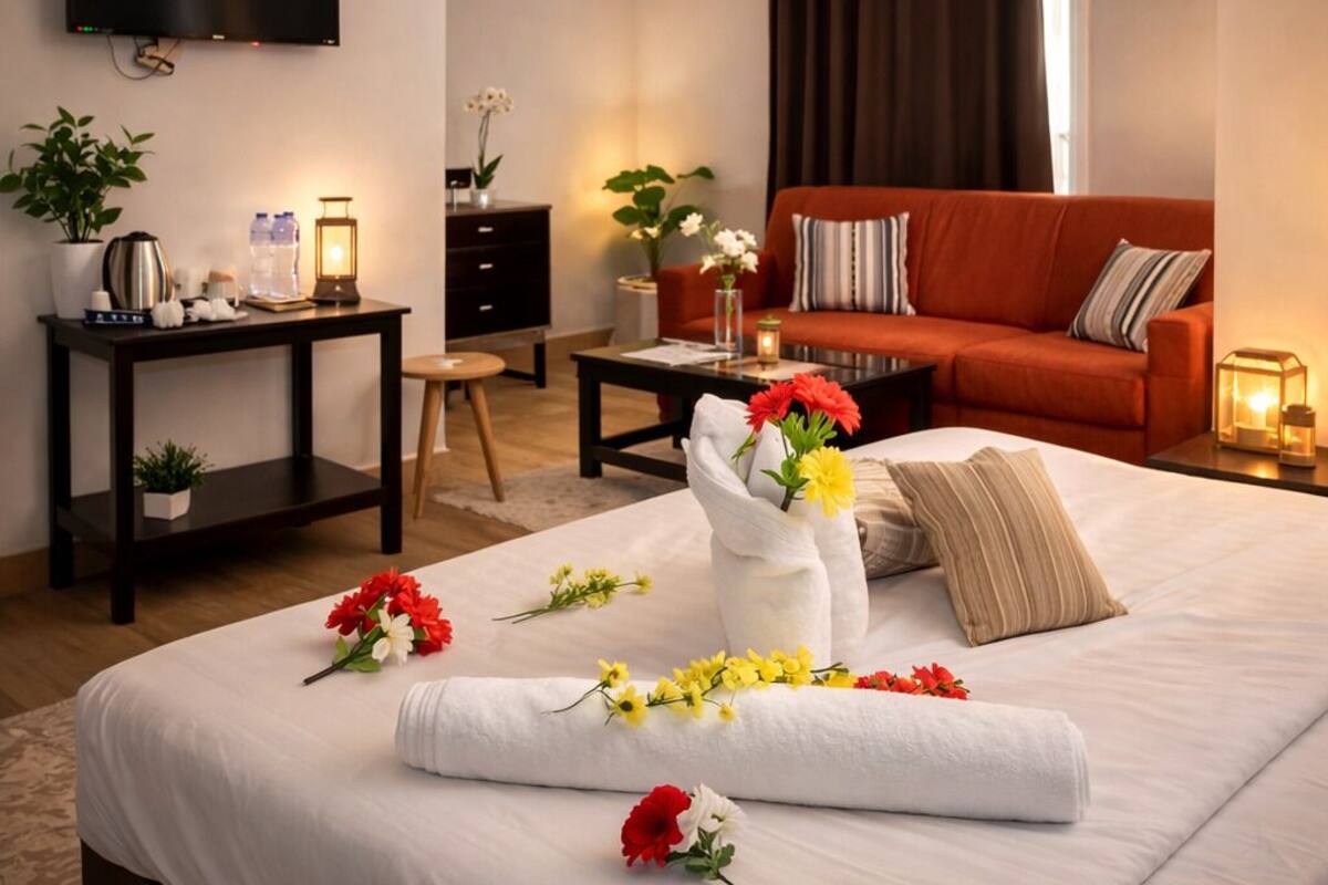 Habitación de hotel con cama, televisor, sofá, mesa de centro y escritorio con lámpara.