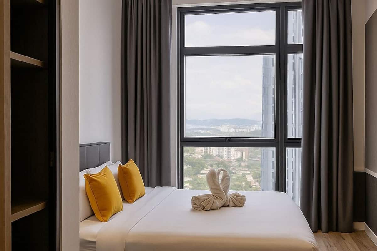 Een hotelkamer met een groot raam, een bed met witte beddengoed en een houten vloer.