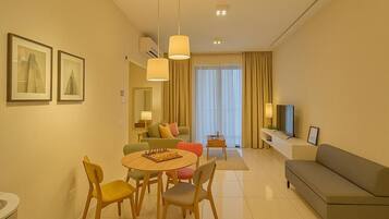 Ein modernes Wohnzimmer mit Sofa, Fernseher, Essbereich mit Tisch und Stühlen sowie zwei gerahmten Bildern an der Wand.