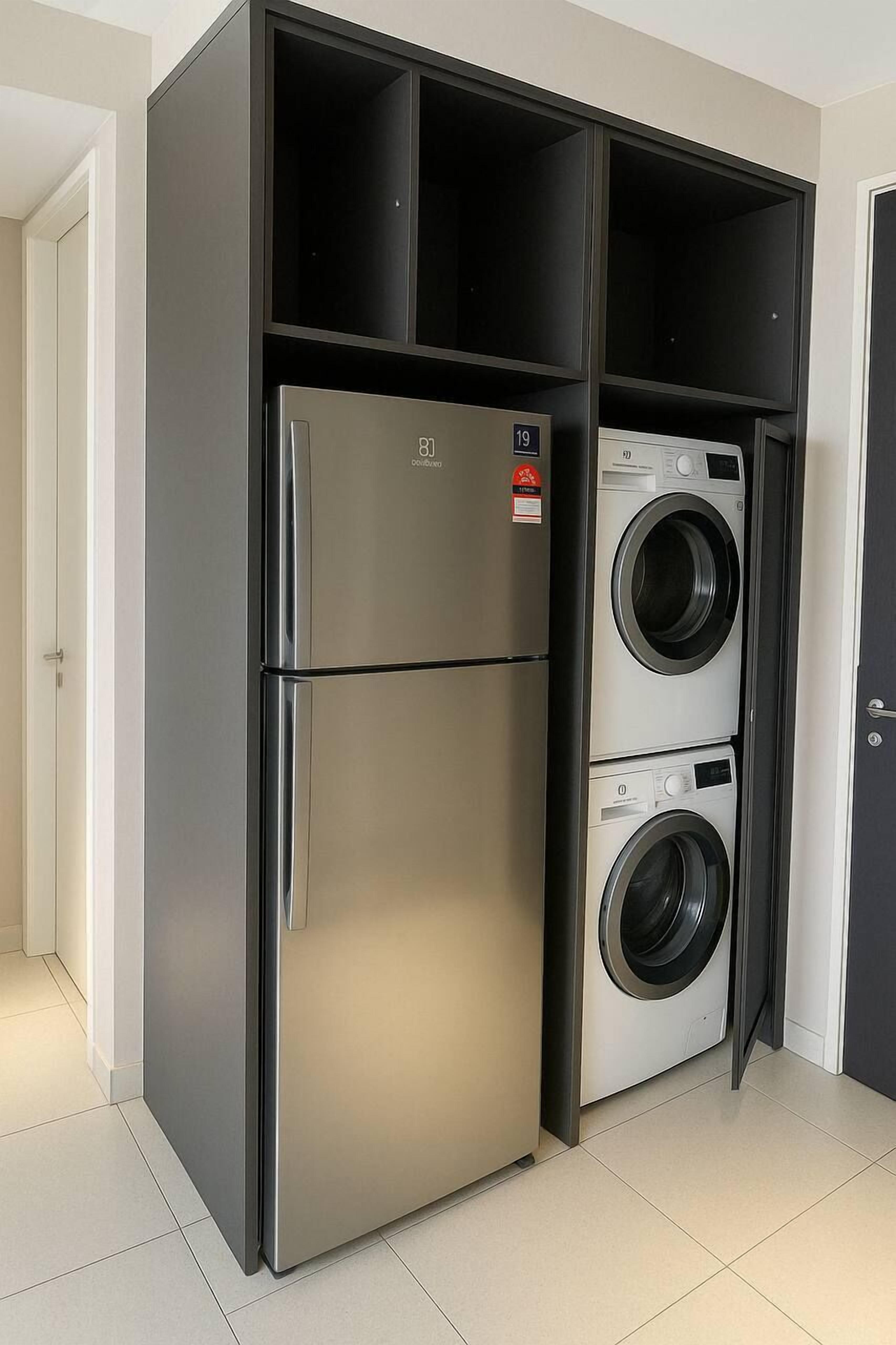 A compact kitchen with a built-in stainless steel refrigerator and a double washing machine.