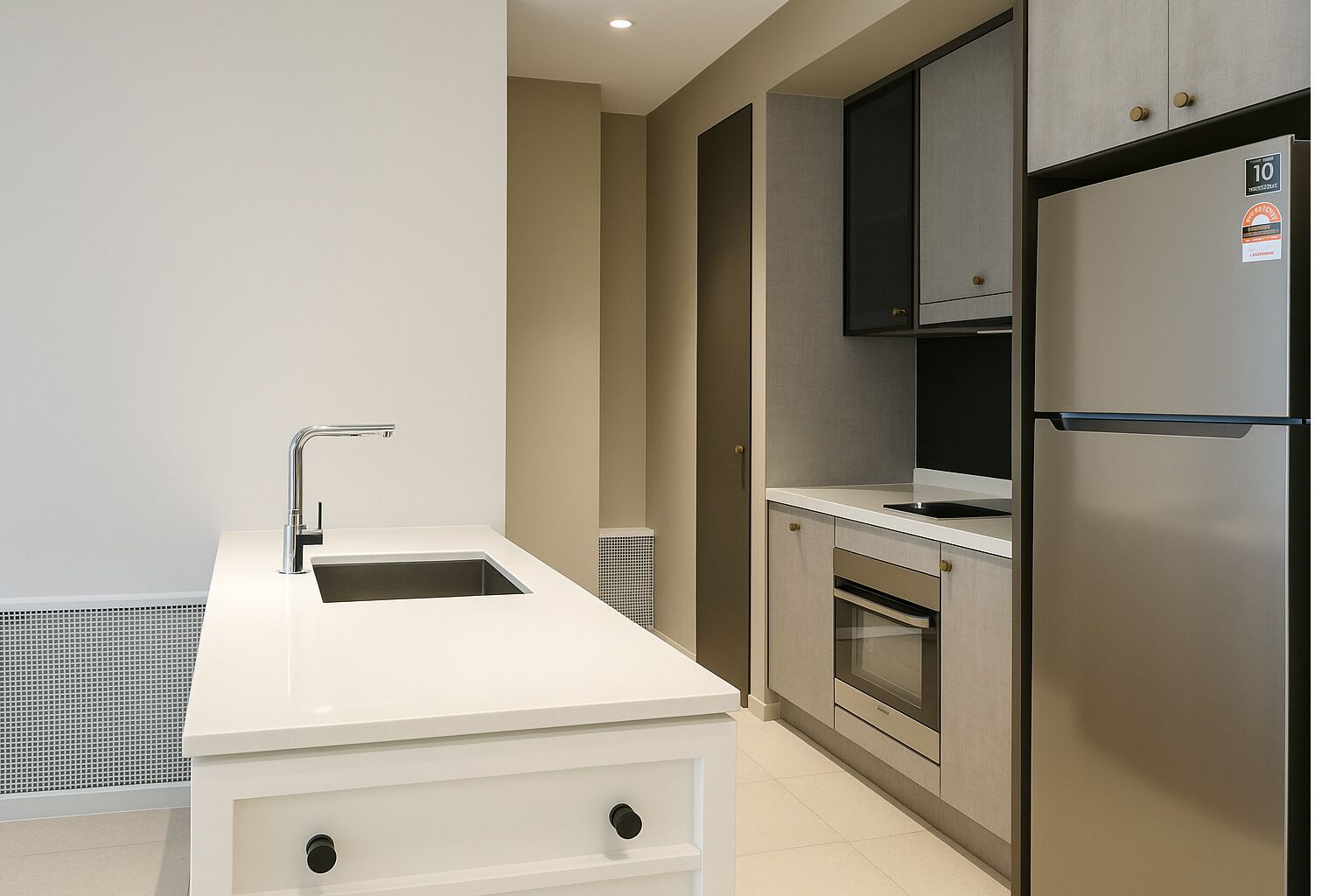 Una cocina moderna con encimera blanca, electrodomésticos de acero inoxidable y horno integrado.