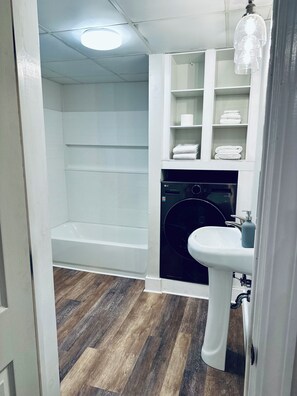 Een moderne badkamer met een ingebouwde wasmachine, een wastafel en een douchehoek.