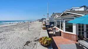 A beachfront property with a patio area, outdoor seating, and a view of the ocean.