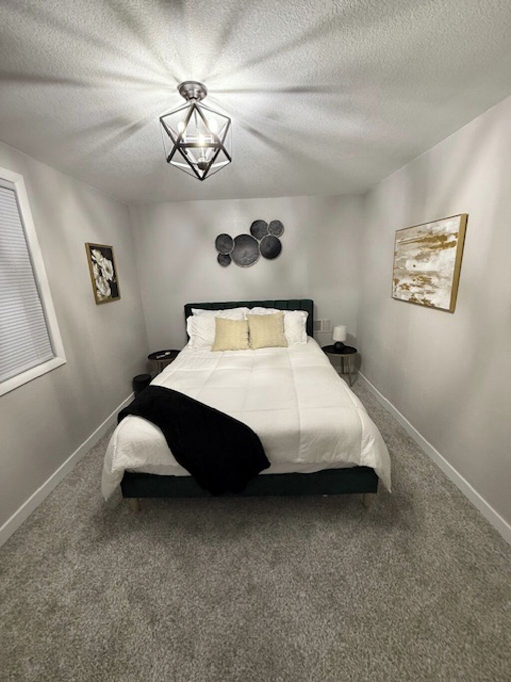 A bedroom with a bed, a nightstand, a lamp, and wall art.