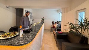 A modern hotel lobby with a marble reception desk, a seating area with a sofa and a coffee table, and a potted plant. - Zeus Suit Görükle (Bursa)