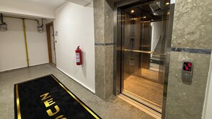 An elevator with a digital display, a fire extinguisher, and a carpet with 'ELEVATOR' written on it. - Zeus Suit Görükle (Bursa)