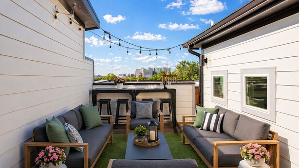Eine Dachterrasse mit einer Sofagruppe, einem Esstisch und Lichterketten.
