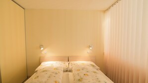A twin room with two beds, each with floral bedding, a wooden headboard, and bedside lamps. - The Cristal apartment house is situated in a quiet, sunny and central location (Leukerbad)