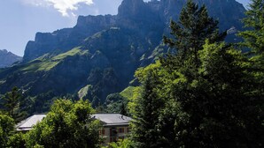 A mountain landscape with a building in the foreground. - The Cristal apartment house is situated in a quiet, sunny and central location (Leukerbad)