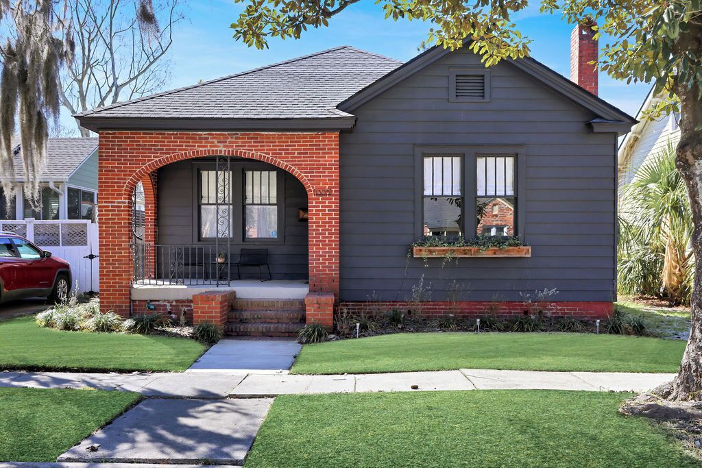 A single-story house with a brick archway entrance, a small porch, and a window with a decorative box.