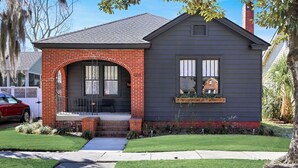 A single-story house with a brick archway entrance, a small porch, and a window with a decorative box.