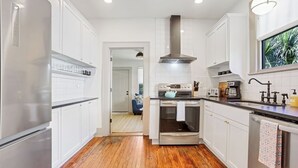 A modern kitchen with white cabinets, a stainless steel range, and a large window.