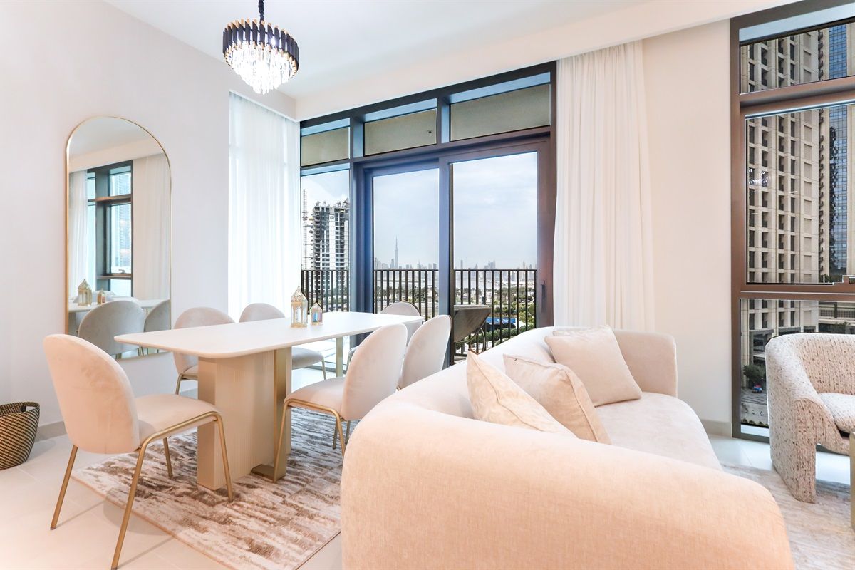 A modern living room with a dining area, large windows, and a view of a cityscape.